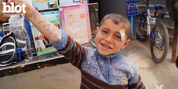 Behind this Syrian boy, you can see the girdles and weight-loss contraptions that are sold to female Syrian refugees at Za'atari refugee camp, demonstrating exactly how low negative body image can go. (Photo by Kirsten Koza)